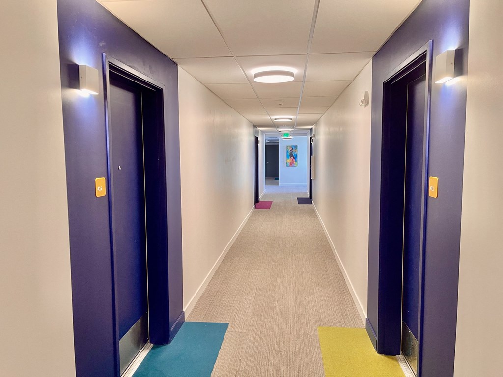 a hallway with blue doors and white walls and a colorful rug on the floor