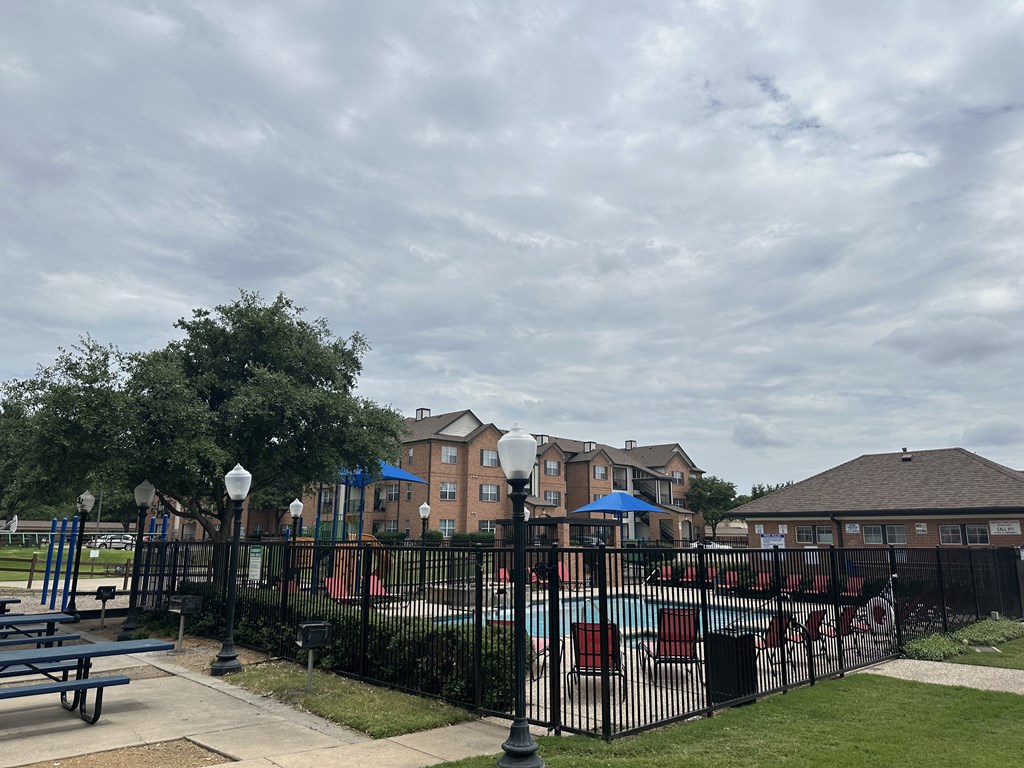 a fenced in pool area with a building in the background
