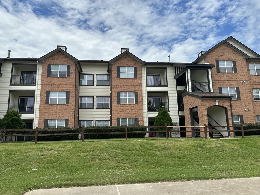 an apartment building on a cloudy day with a green lawn