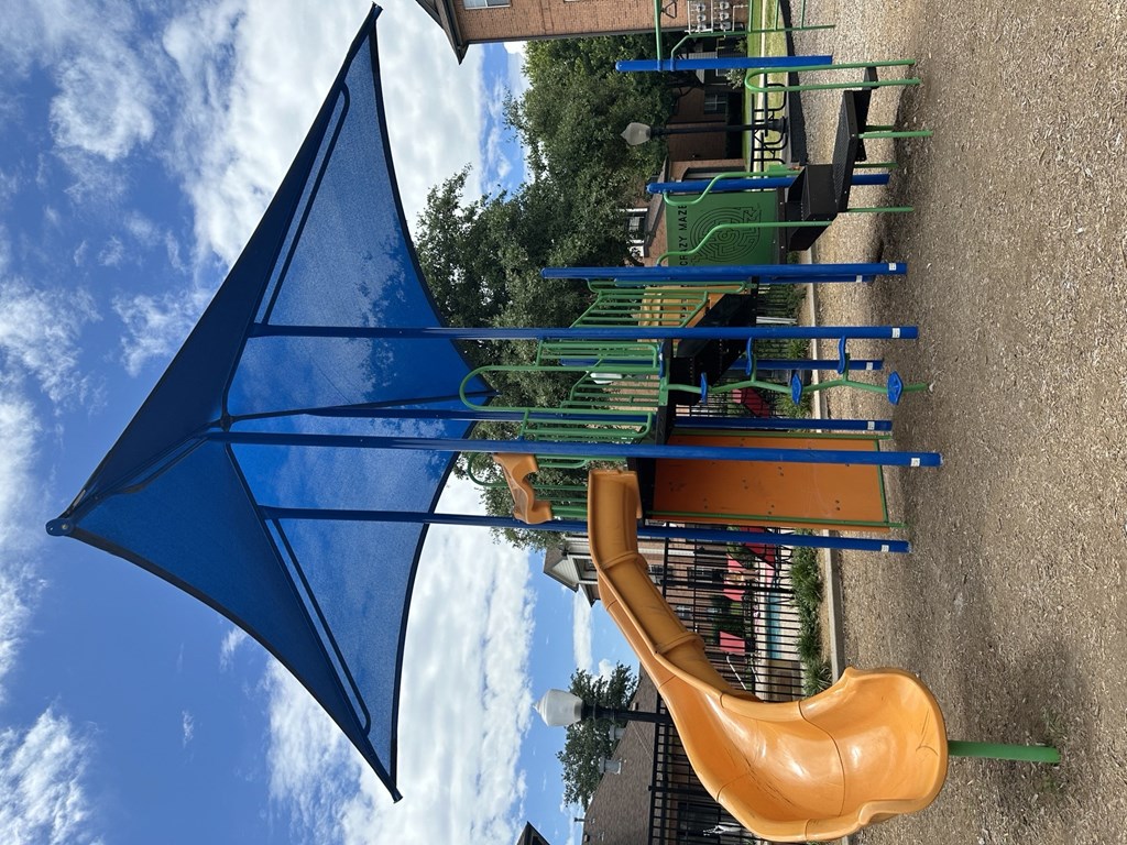 a playground with a slide and a kite in the sky
