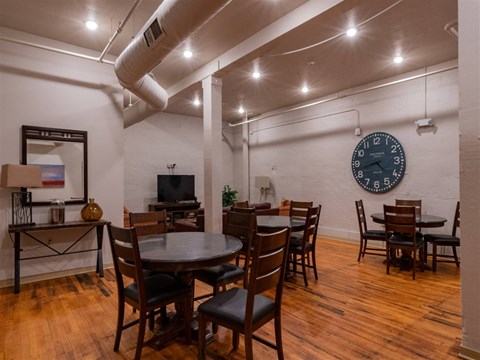 A room with a large table surrounded by chairs and a clock on the wall.