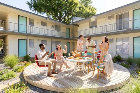 A group of people are gathered around a table on a wooden deck.