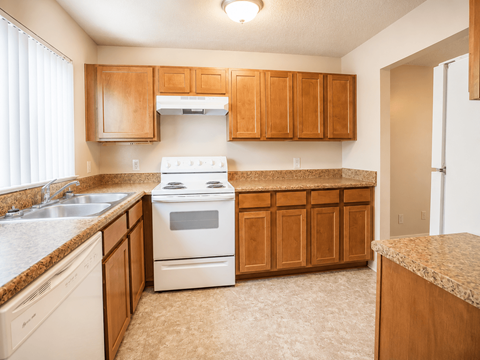 A kitchen with a white stove and wooden cabinets.