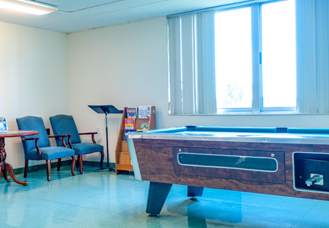 A pool table with a chair and a table in a room.
