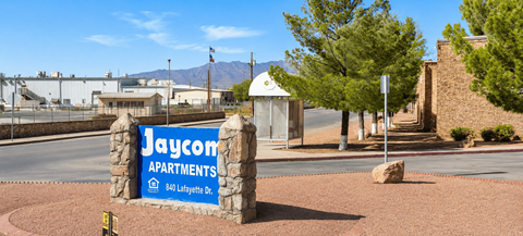 A sign for Jaycom Apartments stands in front of a building.