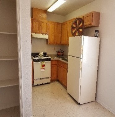 A white refrigerator stands in a kitchen with wooden cabinets.