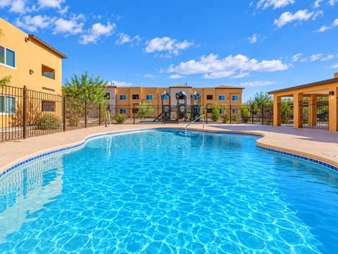 A swimming pool in front of a building with a fence around it.