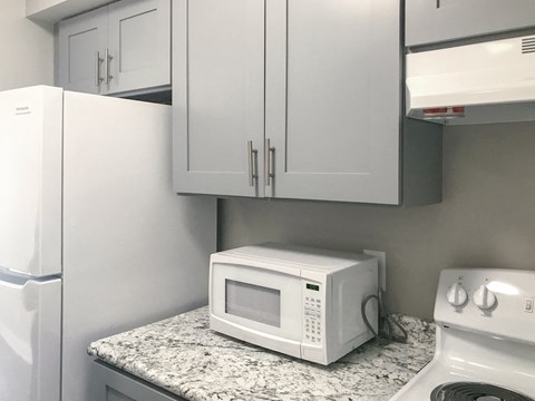 A white microwave oven sitting on a granite countertop in a kitchen.
