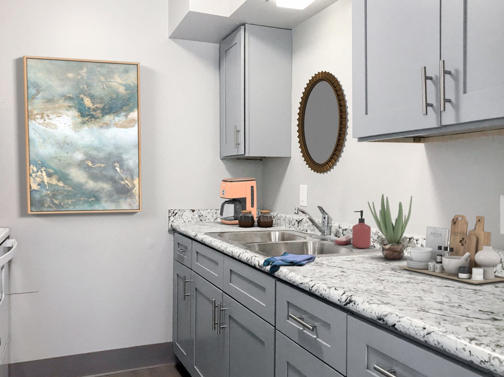 a kitchen with white cabinets and a marble counter top and a sink
