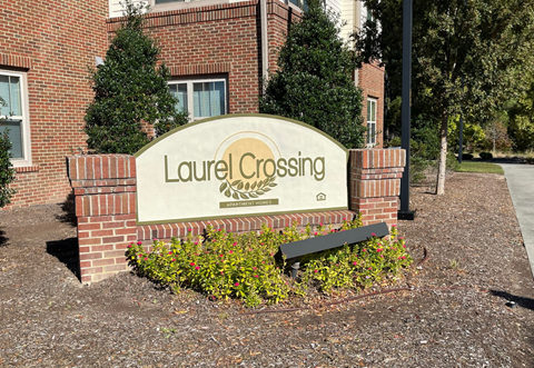 the sign in front of the leasing office of laurel crossing apartments