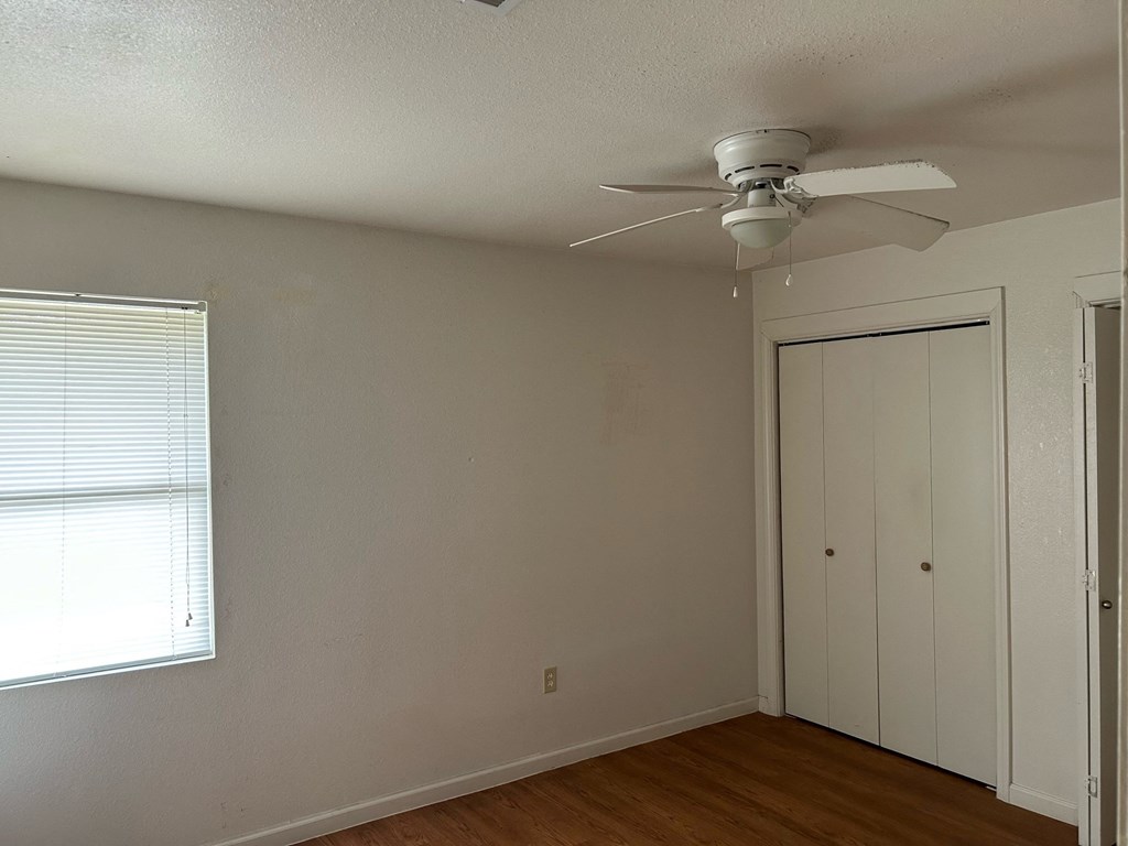 a bedroom with a ceiling fan and a closet