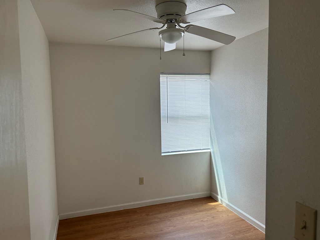 an empty room with a ceiling fan and a window