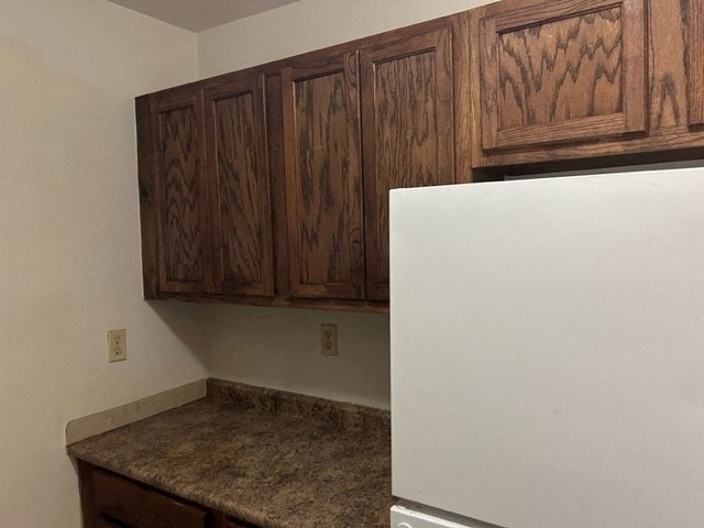 a kitchen with a white refrigerator and wooden cabinets