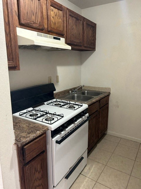 A kitchen with a white stove and wooden cabinets.