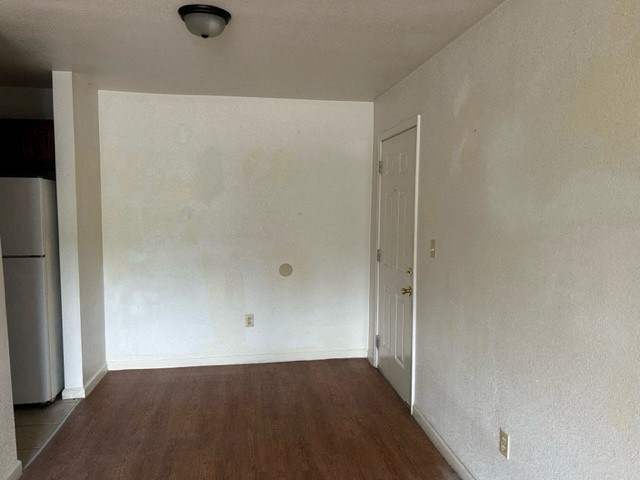 an empty room with white walls and a refrigerator