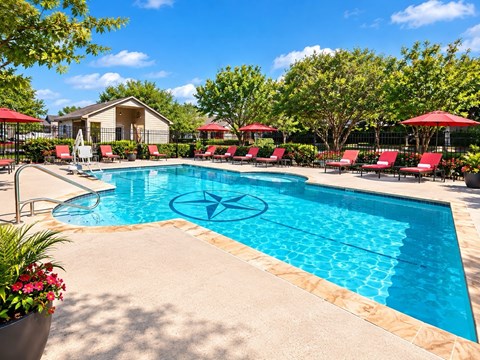 A pool surrounded by red lounge chairs and umbrellas.