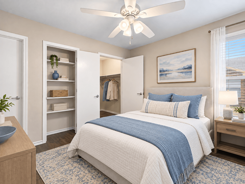 A bedroom with a bed, a ceiling fan, and a painting on the wall.