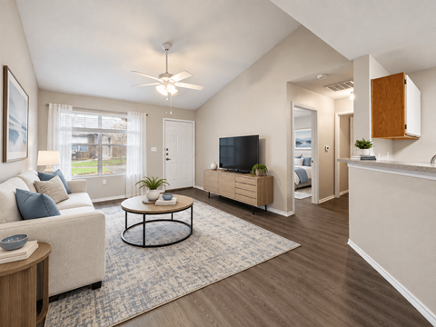 A living room with a white couch, a coffee table, and a flat screen TV.