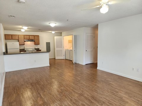 A spacious living room with hardwood floors and a ceiling fan.