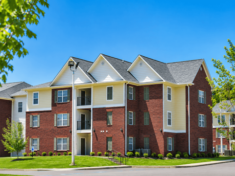 A large red brick apartment building with a white trim and a black roof.