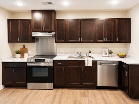 A modern kitchen with dark wood cabinets and stainless steel appliances.