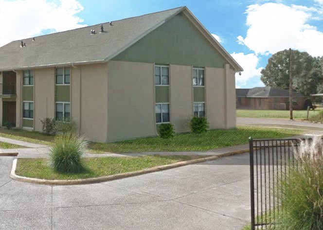 an apartment building with a fence and grass in front of it