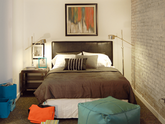 a bedroom with a bed and a brick wall