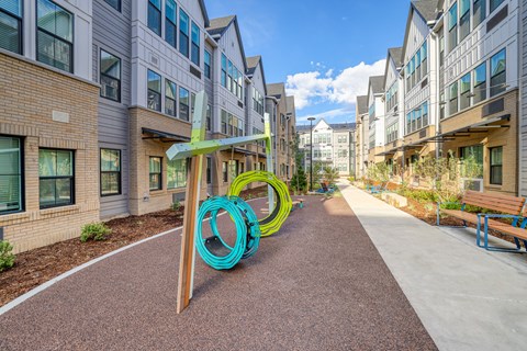 A playground with a slide in the middle of a walkway between buildings.