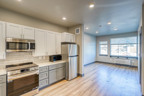 A kitchen with white cabinets and a stainless steel refrigerator.