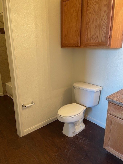 A white toilet in a small room with wooden cabinets.
