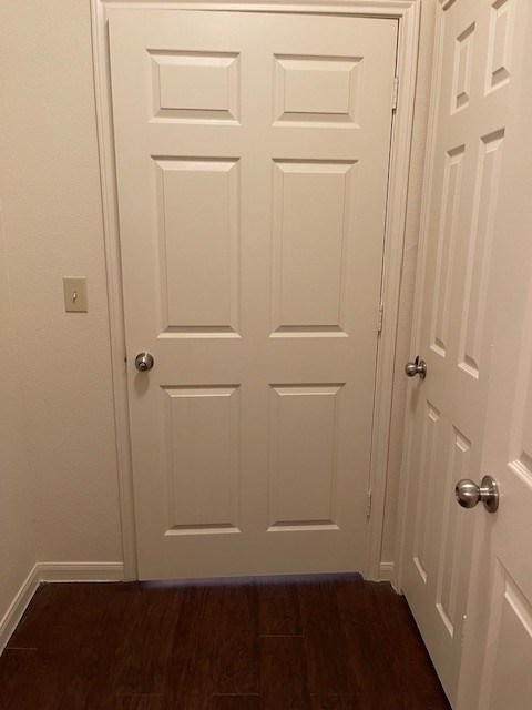 A white door with a silver handle is in the middle of a hallway.