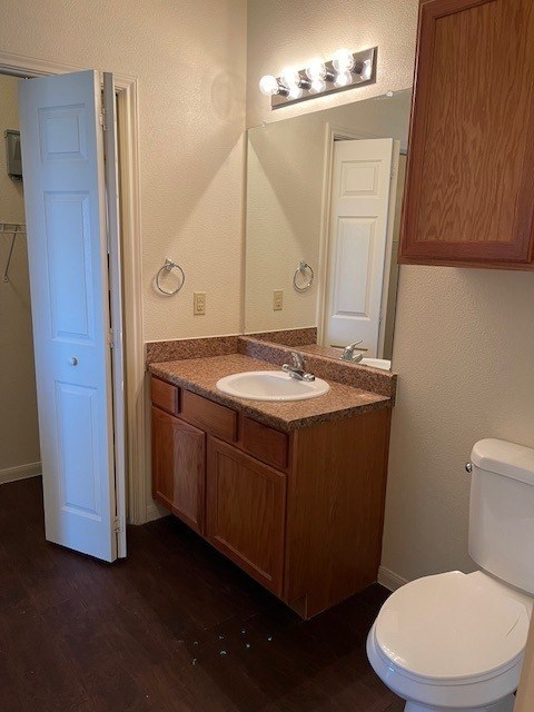 A bathroom with a white toilet, sink, and wooden cabinets.