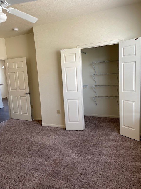 A room with two white doors, one open, and a ceiling fan.