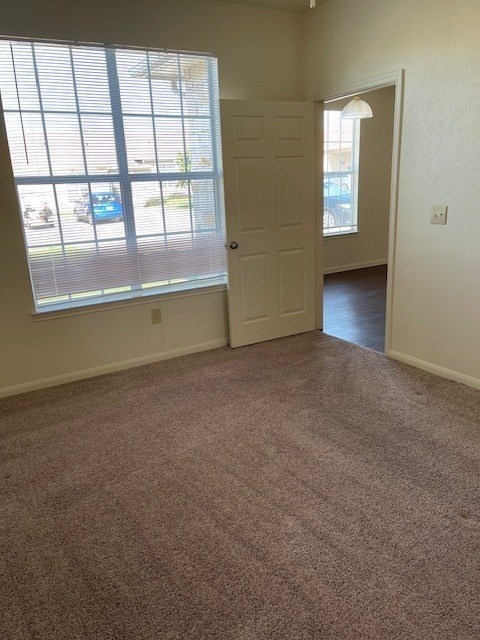 A room with a carpeted floor and a door leading to another room.