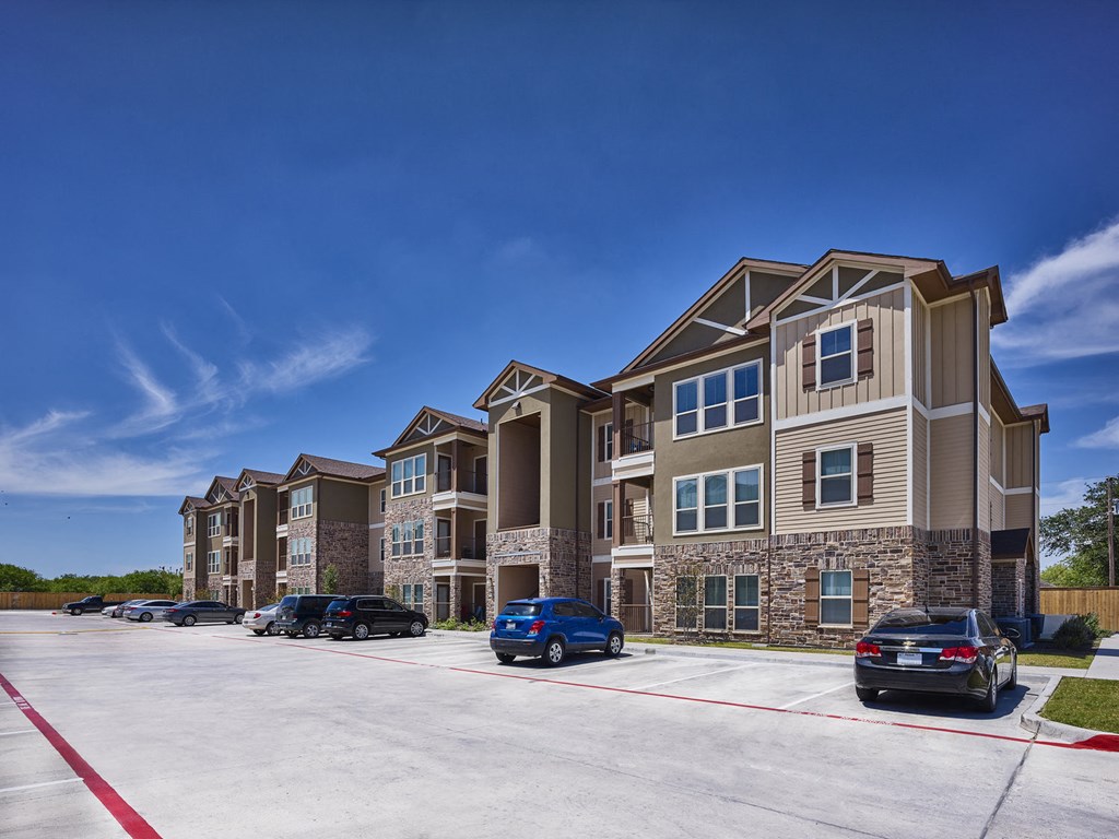 A row of townhouses with cars parked in front.