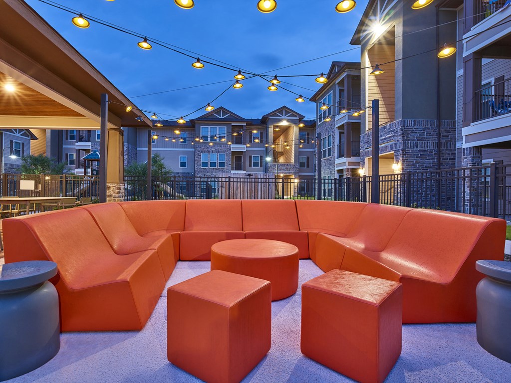 A patio with orange furniture and string lights.