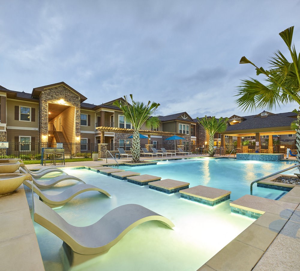 A large outdoor swimming pool with a slide and loungers.