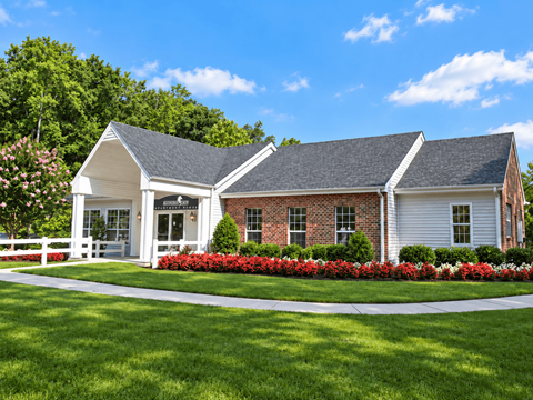 A white house with a red brick chimney and a white fence.