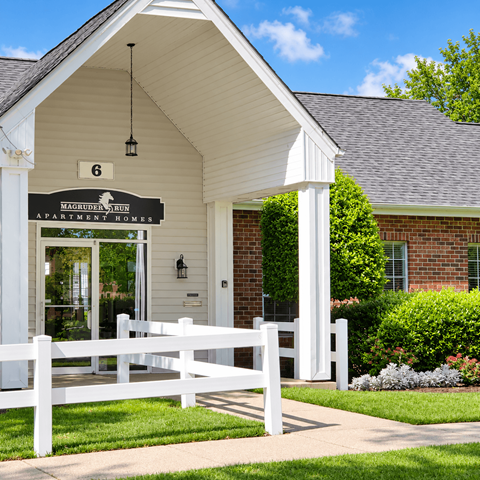 A white house with a sign that says "Magnolia Run Apartment Homes".