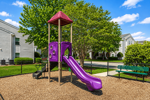 A purple slide in a playground with a red roof.