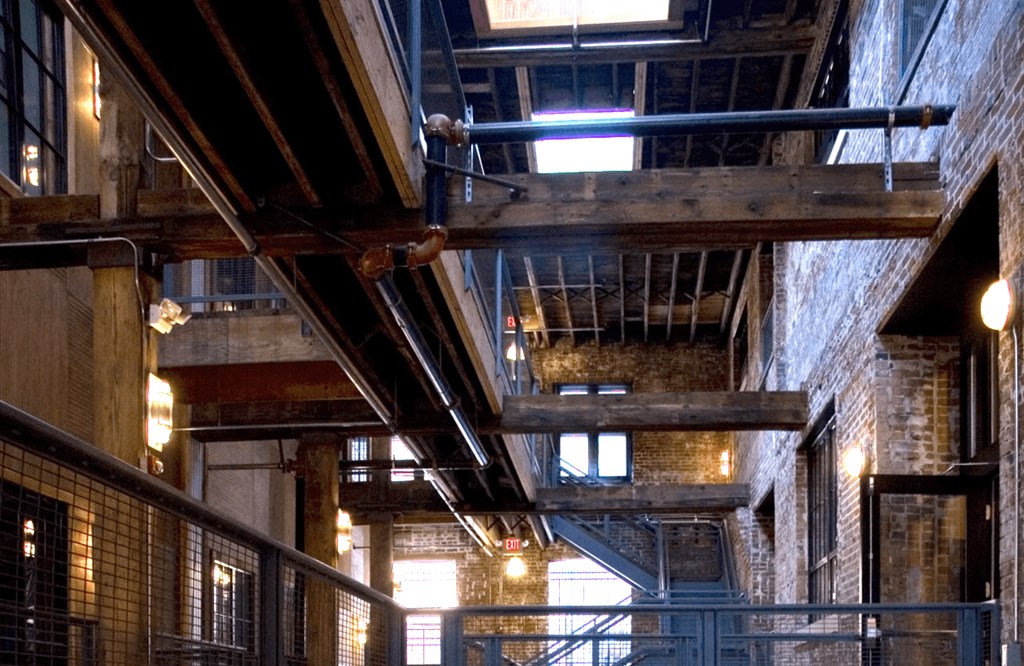 the interior of a building with exposed steel beams and brick walls