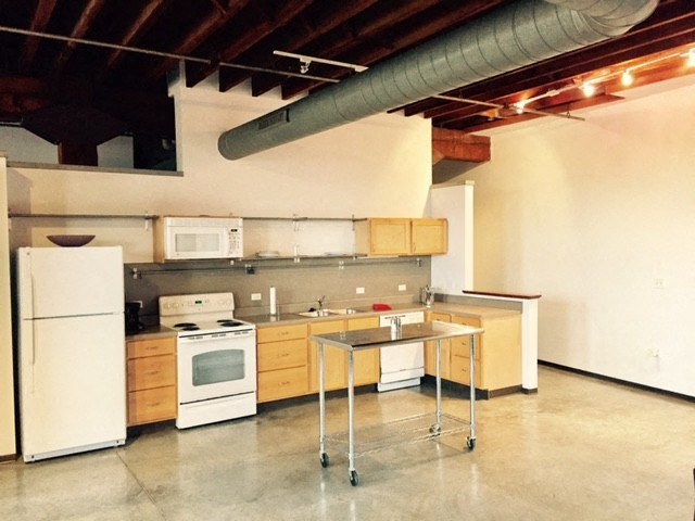 an empty kitchen with white appliances and a table