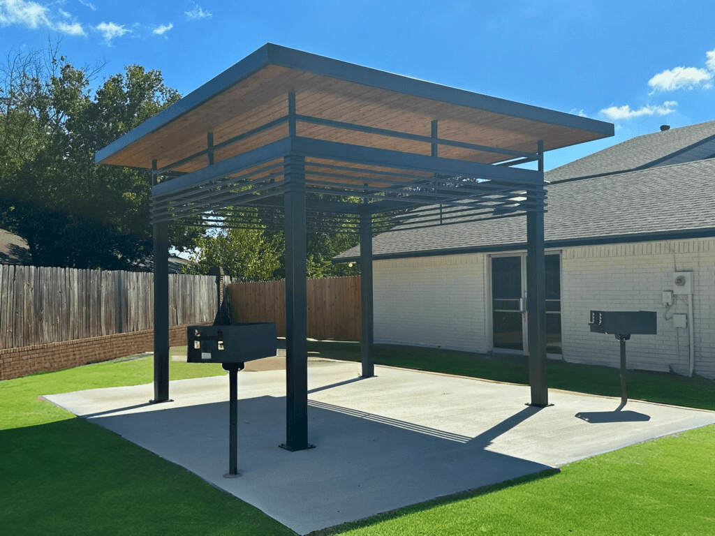 a pergola with two barbecue pits in a backyard at Mammoth at the Orchard Apartments, Rogers  
