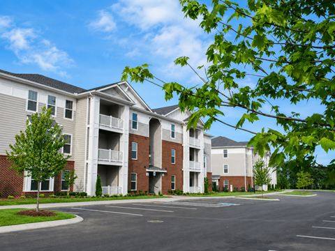 Apartment complex with a parking lot in front.