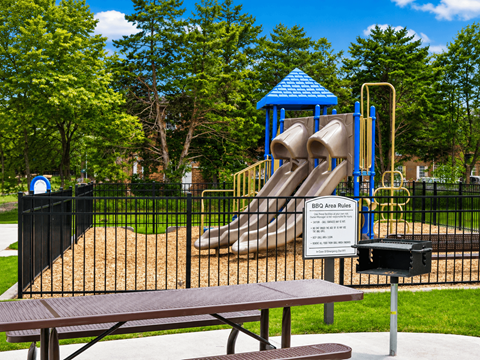 A playground with a slide and picnic table.