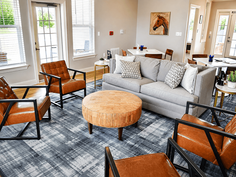 A living room with a grey couch and brown chairs.