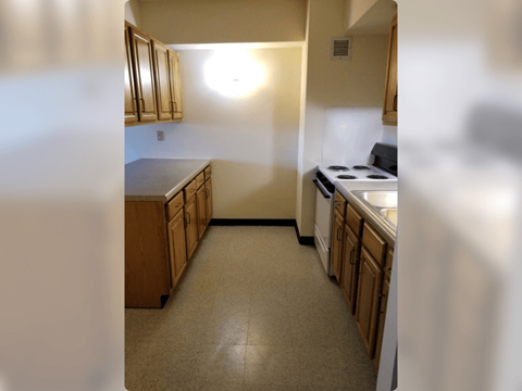 A kitchen with wooden cabinets and a stove top oven.