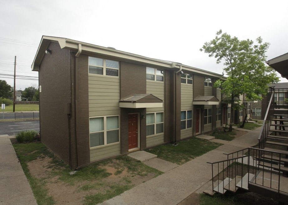 A brown and beige apartment building with a red door.