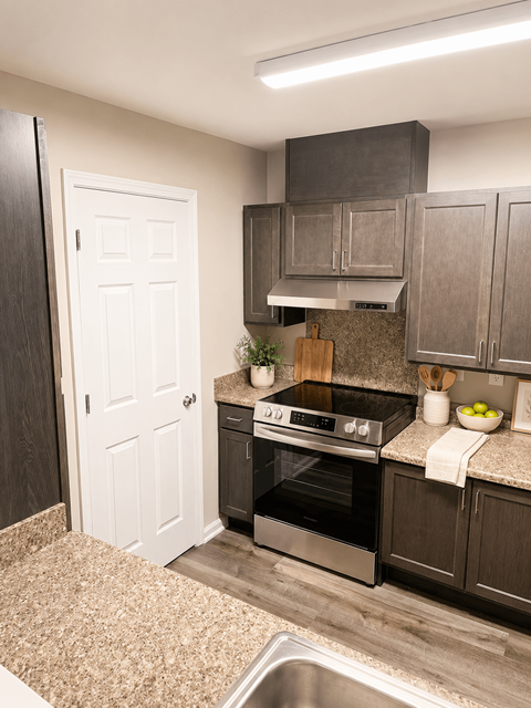 A kitchen with a stove top oven and a white door.