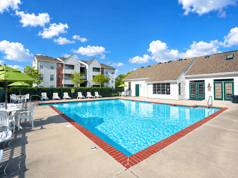 A large swimming pool with a red border and white lounge chairs.